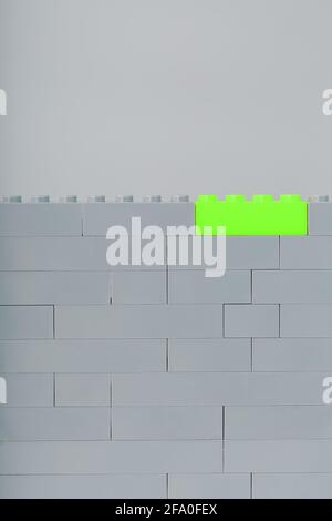 A wall made of children's construction kit parts with bright green bricks. Concept Stock Photo