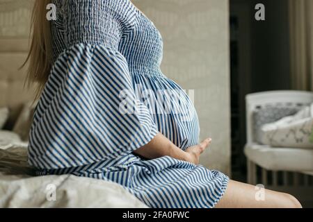 A side view of a pregnant woman touching her belly. A cropped image of a mother to be holding her pregnancy bump. Stock Photo