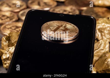 Bitcoin cryptocurrency on smartphone with gold nuggets. Investment and store of value concept. Stock Photo