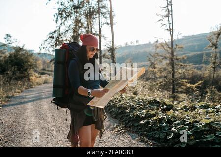 A female hiker reading a map. A portrait of a woman with a backpack checking a map. Stock Photo