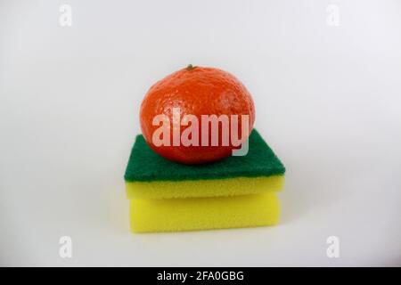 A tangerine on a kitchen yellow green sponge isolated on white background Stock Photo