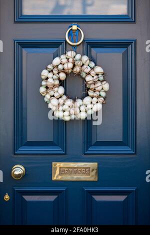 Easter egg wreath door decoration on a dark blue painted front door in an English village in Spring Stock Photo