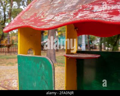 Blurry image of an old wooden colorful playhouse at children playground in a park. Closeup of a public wendy's house. Rope park in the background. Stock Photo