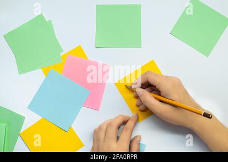 Female hand with a pencil and many blank stickers for writing isolated on a white background. Writing ideas Stock Photo