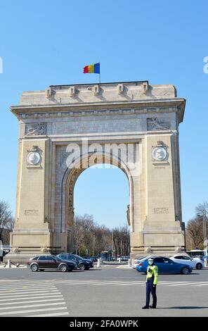 BUCHAREST, ROMANIA - 11 APRIL 2021: A policeman directs traffic at the country's triumphal arch, first built after Romania gained independence in 1878 Stock Photo