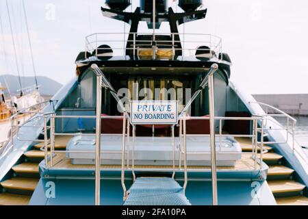 Stern trawl of a beautiful motor white yacht with a wooden ladder. Inscription: PRIVATE No Boarding. Close-up Stock Photo