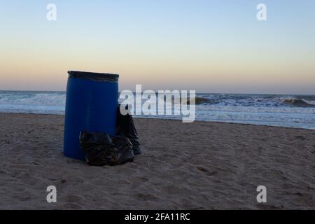 Trash can on the sand at sunrise. Stock Photo