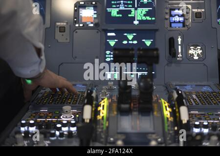 Hand of the airplane pilot pushing a button in the cockpit of a commercial flight simulator Stock Photo