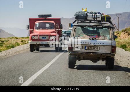 Midelt, Morocco - April 11, 2015. Fully loaded off road car on road trip passing by red vintage truck Stock Photo