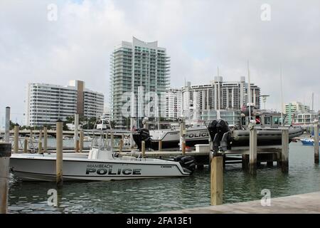 Miami Beach Police Marine Patrol boat and tug boat parked on a deck by the bay. Docked. Located at Maurice Gibb Memorial Park Stock Photo