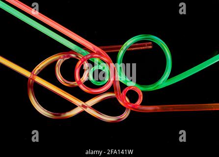 Three colourful drinking straws in interesting shapes arranged to form an abstract image on pure black background. Stock Photo