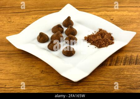 Cocoa dusted chocolate truffles with cocoa powder on white snack plate on table Stock Photo