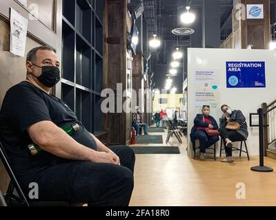 New York, USA. 07th Apr, 2021. Bayro (l) sits in the 24-hour vaccination center at Citi Field stadium. The 49-year-old has been vaccinated himself, this time bringing his daughter in for the appointment. Vaccinations are given around the clock at the stadium. (to dpa 'Vaccination champion America: injection in the supermarket and vaccination at night') Credit: Benno Schwinghammer/dpa/Alamy Live News Stock Photo