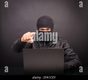 Laptop computer hacker point hand - Male thief stealing data from laptop computer on black background Stock Photo