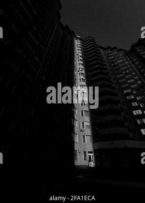 Dramatic and moody shot of a high rise building with shallow sunlight in grayscale Stock Photo