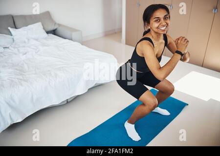 Cheerful young woman having morning workout at home Stock Photo