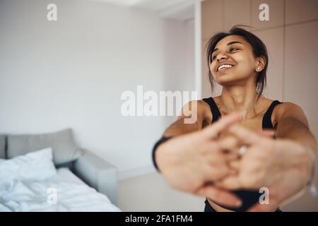 Joyful young woman doing morning gymnastics at home Stock Photo