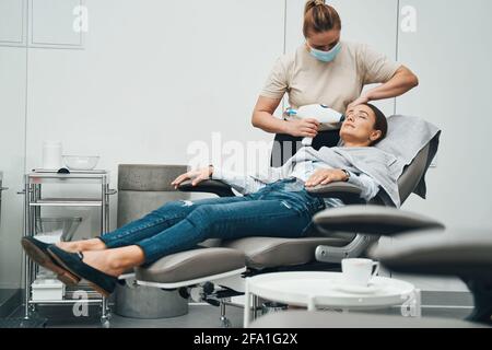Beautician in a protective mask performing a facial rejuvenation treatment Stock Photo