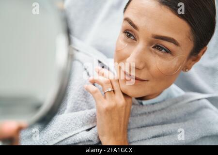 oncentrated beauty salon client examining her facial skin Stock Photo