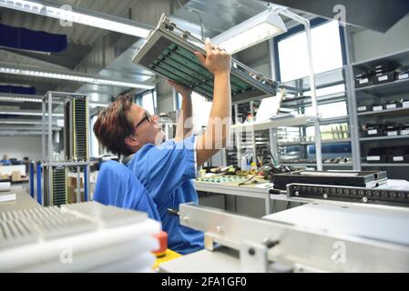 quality control - woman checking motherboard - working in the production of a factory for electronics Stock Photo