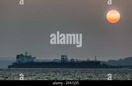 Whitegate, Cork, Ireland. 22nd April, 2021.Rising Sun begins to burn off the fog and mist over the oil tanker Waikiki that is berthed at the refinery at Whitegate, Co. Cork, Ireland.  - Credit; David Creedon / Alamy Live News Stock Photo