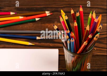 Colorful pencils and white sheets of paper on a wooden table. Close-up selective focus. Stock Photo