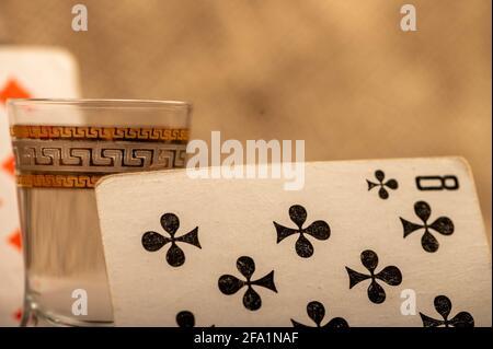 Playing cards and a glass of vodka on a table covered with coarse burlap. Close-up, selective focus. Stock Photo