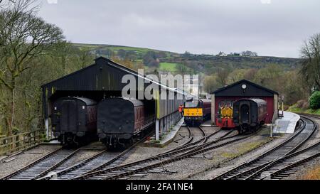 Historic diesel train or loco, railway worker climbing from cab, vintage coaches in engine sheds) - Oxenhope Station sidings, Yorkshire, England, UK. Stock Photo