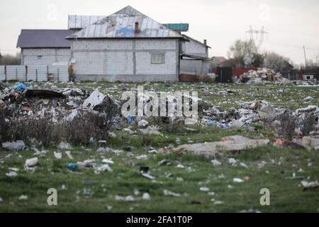Bolintin, Romania - April 2, 2021: Piles of industrial and home waste lay on a field near inhabited houses. Stock Photo