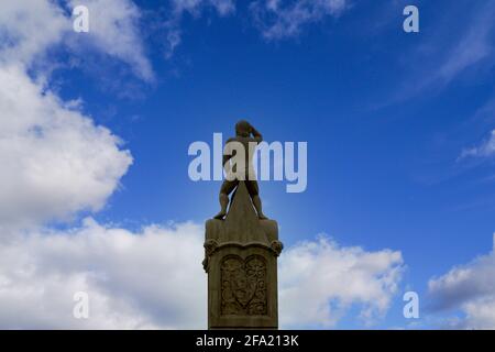 Rear view of sculpture on Old Stone Bridge under cloudy sky in Regensburg, Germany Stock Photo