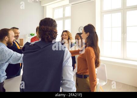 Team of happy business colleagues and friends standing in circle and joining hands Stock Photo