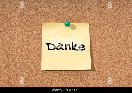 Thanks word in german language on yellow note on cork board Stock Photo