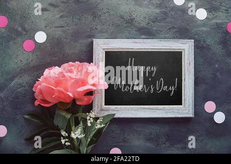 Happy birthday card with peony and paper confetti, circles. Single flower and white frame on black, dark grey distressed textured background. Creative Stock Photo
