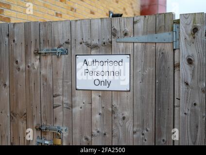 Black and white metal sign on a wooden gate with metal hinges and padlock. Stock Photo