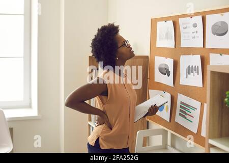 Young african american woman employee standing near board with graphs and charts Stock Photo