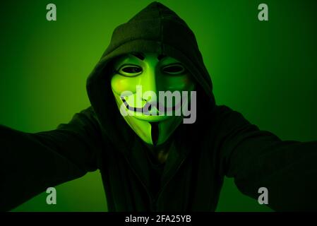New York, USA - 22 april 2021: man wearing vendetta mask with hoodie on black background. This mask is symbol for Anonymous hackers group and for anti Stock Photo