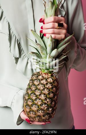 Cropped view of woman holding fresh pineapple isolated on pink Stock Photo