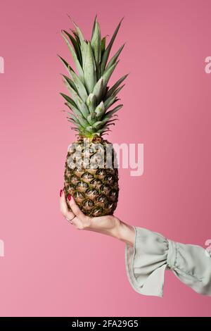 Cropped view of woman holding pineapple isolated on pink Stock Photo