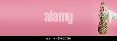 Cropped view of woman holding leaves of pineapple isolated on pink, banner Stock Photo