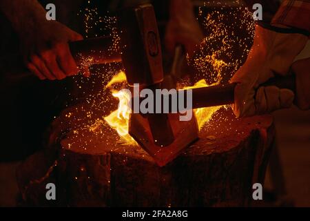 Blacksmiths hit molten metal with hammers close up Stock Photo