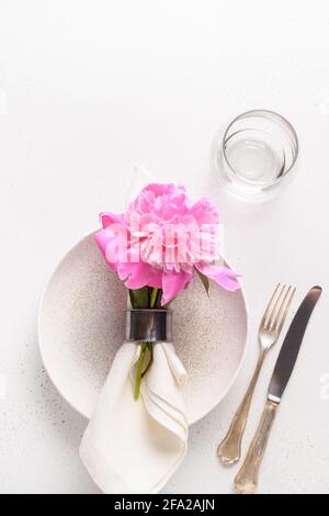 Elegance romantic table setting with pink peony flowers on a white table. View from above. Vertical format. Stock Photo