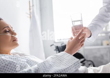 diseased african american woman taking glass of water from doctor in clinic Stock Photo