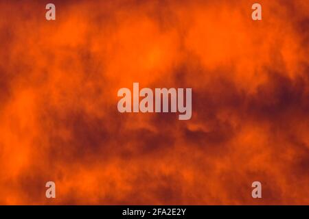 Abstract concept background image of dark clouds in fiery enhanced orange winter sunset sky England Great Britain United Kingdom UK Stock Photo