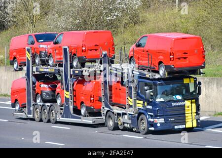 Loaded lorry truck car distribution transporter trailer to transport & deliver six new red Peugeot Expert brand of vans driving on motorway England UK Stock Photo