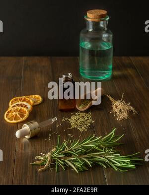 Composition of rosemary branches, chopped dried rosemary, dried orange slices and mint drink, as well as a herbal cosmetic Stock Photo