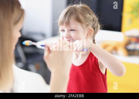 Dentist shows girl how to brush her teeth properly Stock Photo