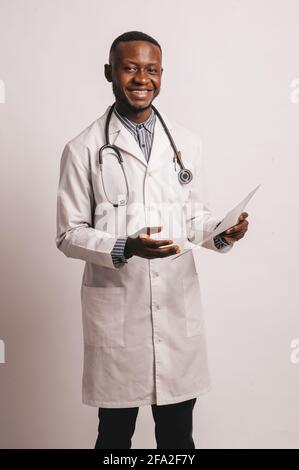 black skinned young medic smiling standing on a white background with papers in hand Stock Photo