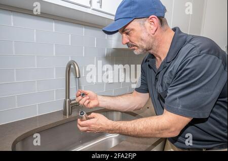 Plumber repairing a kitchen faucet spray nozzle Stock Photo