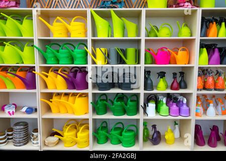 Colorful watering cans on display in shelves, garden centre Stock Photo