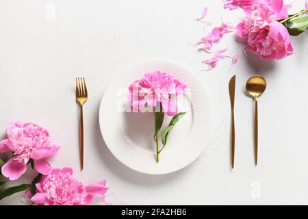 Festive spring table setting with pink peony flowers on a white table. View from above. Banquet Invitation. Stock Photo
